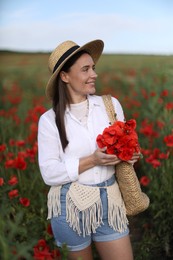 Photo of Smiling woman in hat with bag of poppy flowers in wildflower meadow