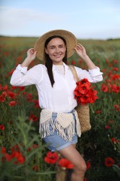 Photo of Portrait of smiling woman in hat with bag of poppy flowers in wildflower meadow