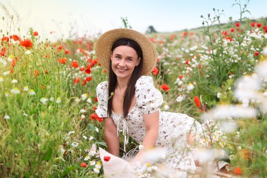 Photo of Smiling woman in hat among wildflowers in meadow