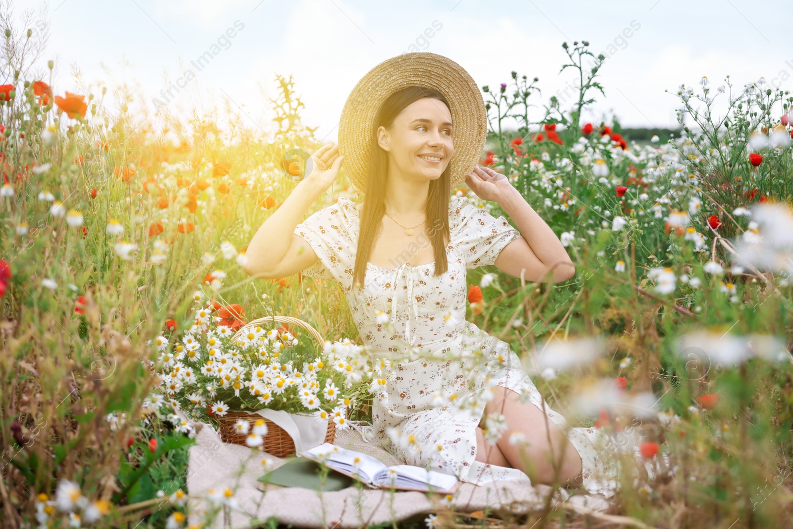 Photo of Smiling woman in hat posing in morning wildflower meadow