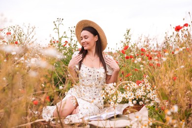Photo of Smiling woman in hat posing in wildflower meadow