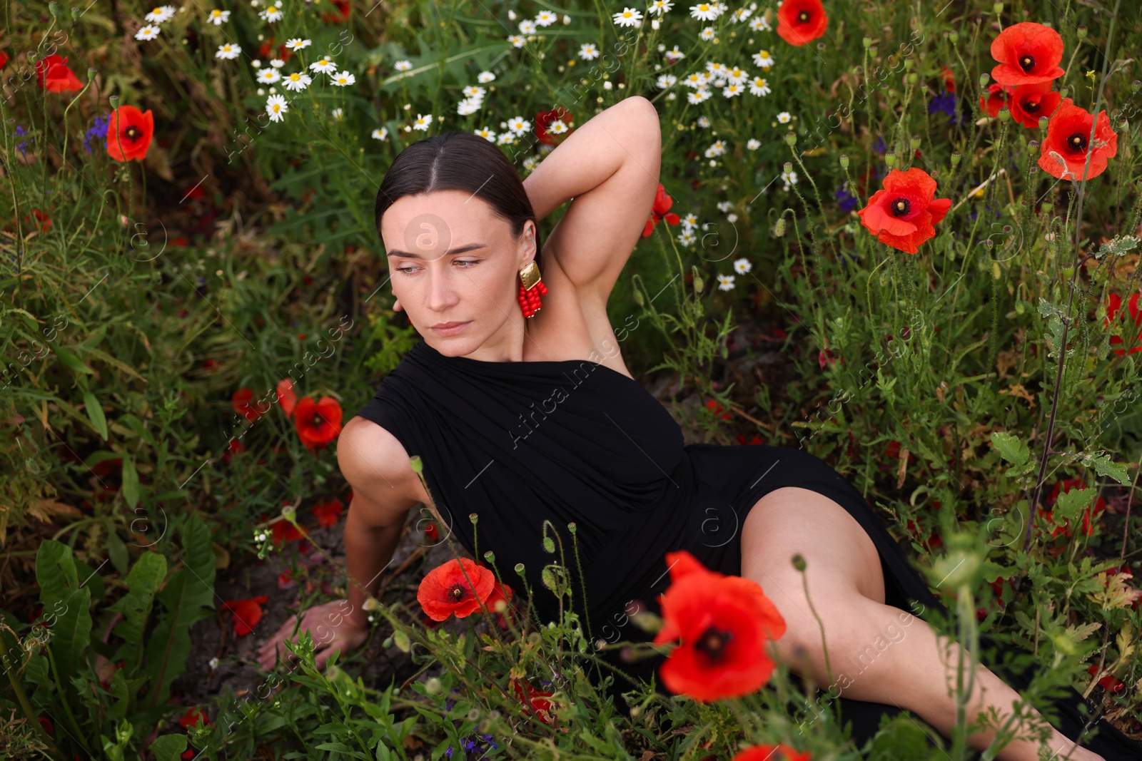 Photo of Beautiful woman posing among wildflowers in meadow