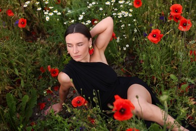 Photo of Beautiful woman posing among wildflowers in meadow