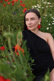 Photo of Beautiful woman posing among wildflowers in meadow