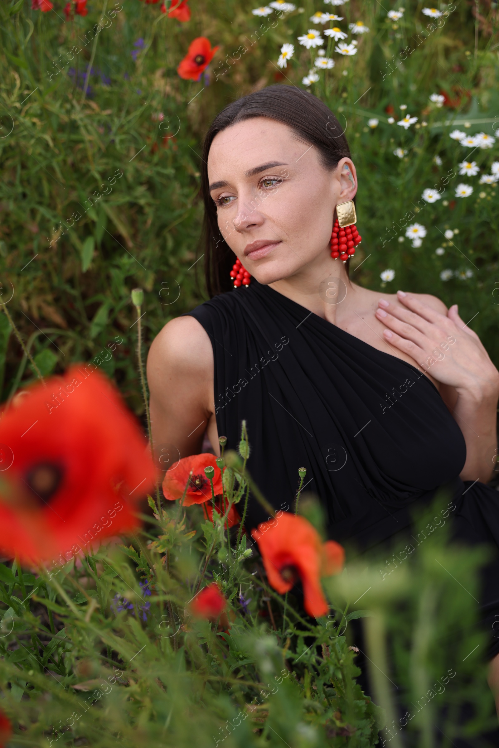Photo of Beautiful woman posing among wildflowers in meadow