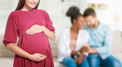 Image of Surrogate mother and intended parents indoors, selective focus