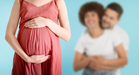 Image of Surrogate mother and intended parents against light blue background, selective focus