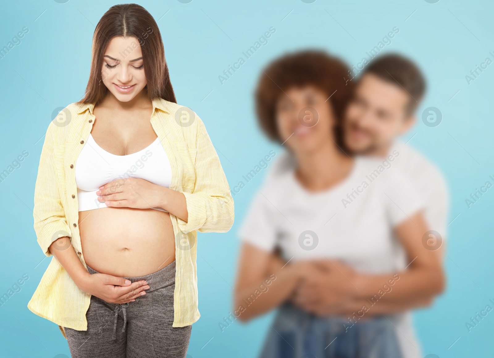 Image of Surrogate mother and intended parents against light blue background, selective focus