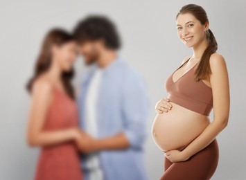 Image of Surrogate mother and intended parents against light grey background, selective focus