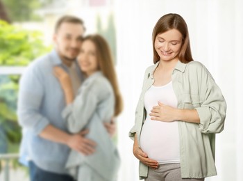 Image of Surrogate mother and intended parents indoors, selective focus