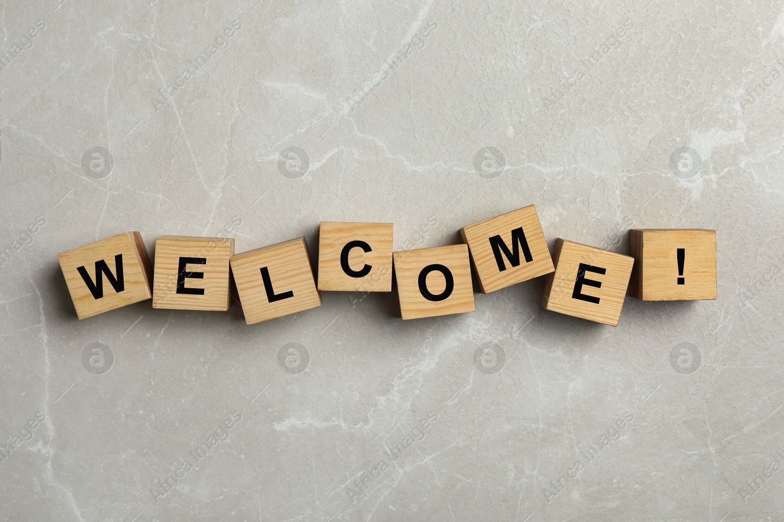 Word Welcome and exclamation mark made of wooden cubes on grey marble background, top view Image of Word Welcome and exclamation mark made of wooden cubes on grey marble background, top view