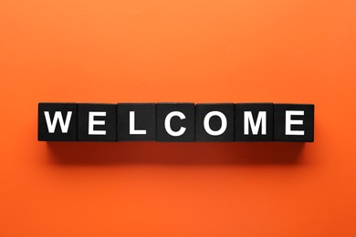 Image of Word Welcome made of black cubes on orange background, top view