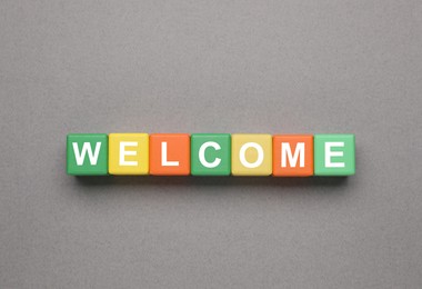 Image of Word Welcome made of colorful cubes on grey background, top view