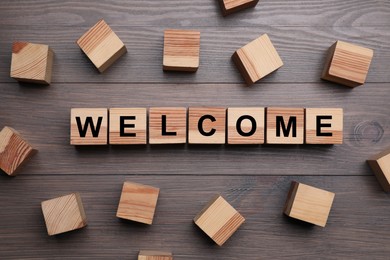 Image of Word Welcome made of wooden cubes on table, flat lay