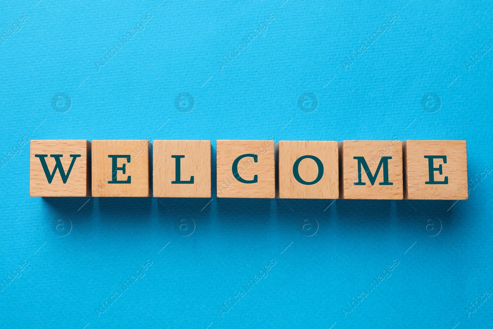 Word Welcome made of wooden cubes on light blue background, top view Image of Word Welcome made of wooden cubes on light blue background, top view