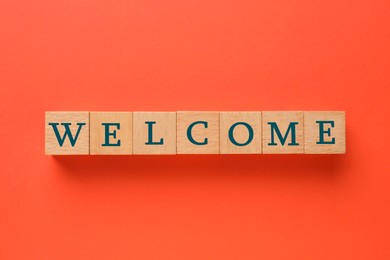 Image of Word Welcome made of wooden cubes on red background, top view