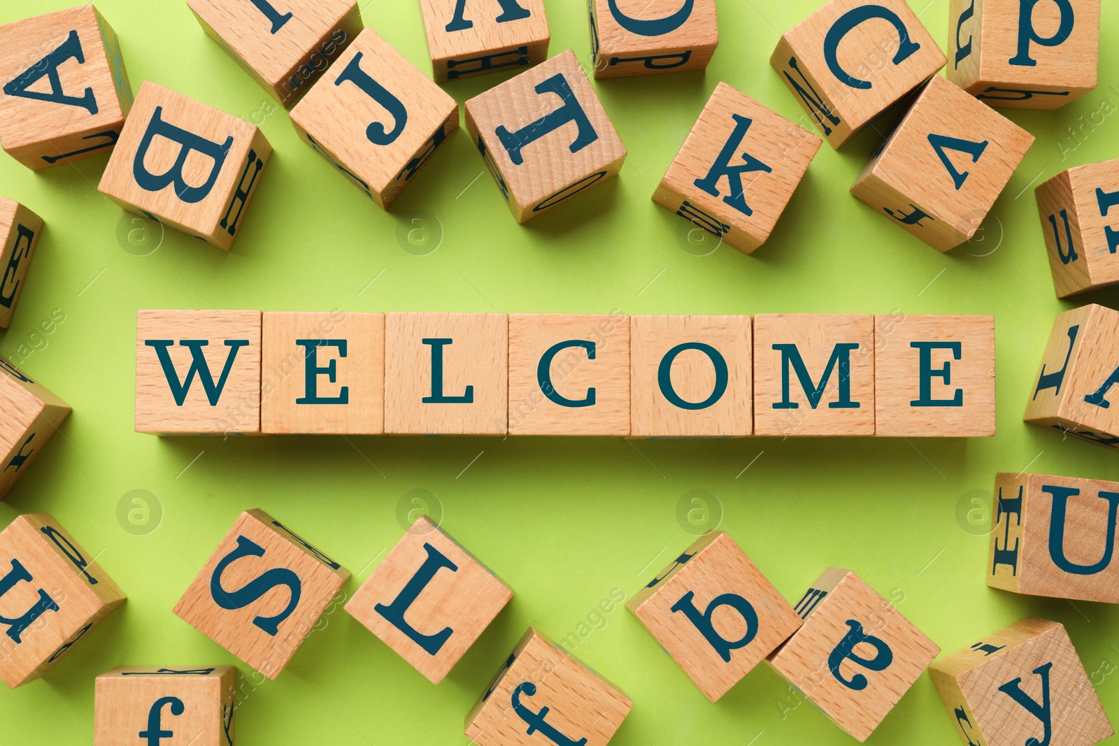 Word Welcome made of wooden cubes on light green background, flat lay Image of Word Welcome made of wooden cubes on light green background, flat lay
