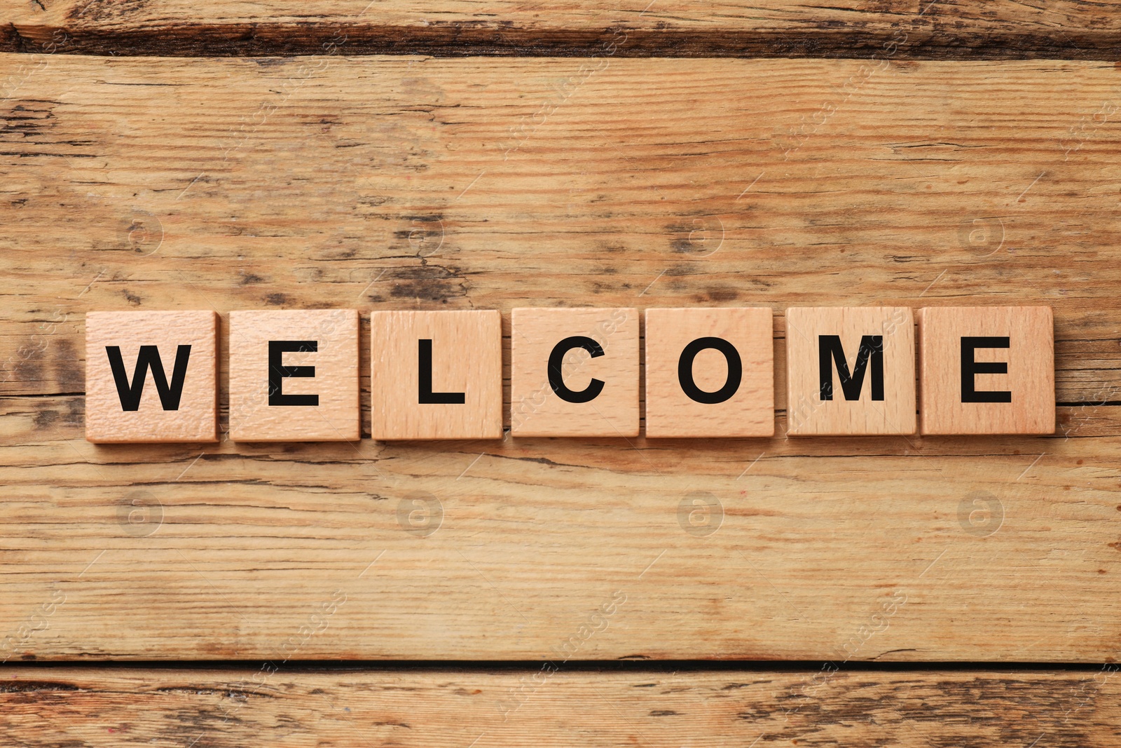 Word Welcome made of wooden cubes on table, top view Image of Word Welcome made of wooden cubes on table, top view