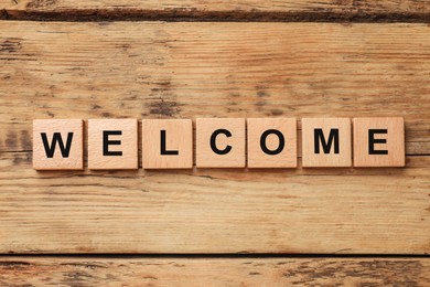 Image of Word Welcome made of wooden cubes on table, top view