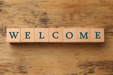 Image of Word Welcome made of wooden cubes on table, top view