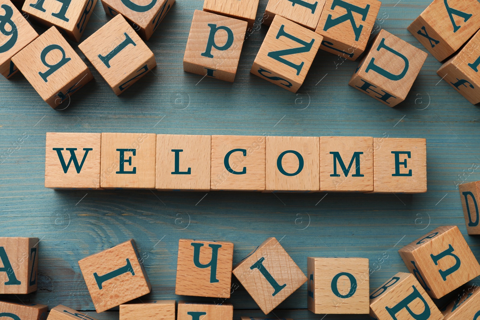 Word Welcome made of wooden cubes on light blue table, flat lay Image of Word Welcome made of wooden cubes on light blue table, flat lay