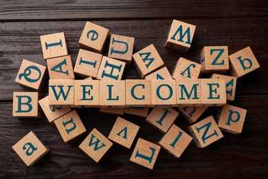 Image of Word Welcome made of wooden cubes on table, top view