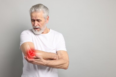 Image of Arthritis. Senior man suffering from pain in elbow on grey background, space for text. Illustration of joint inflammation