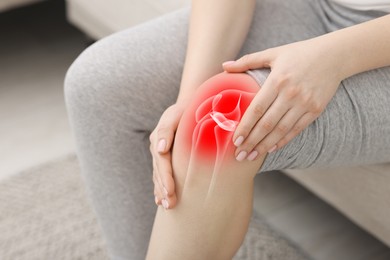 Image of Arthritis. Woman suffering from pain in knee on sofa indoors, closeup. Illustration of joint inflammation on her leg
