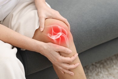 Image of Arthritis. Woman suffering from pain in her knee on sofa, closeup. Illustration of joint inflammation on his leg