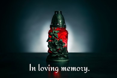 Image of In loving memory. Red grave light on table in darkness