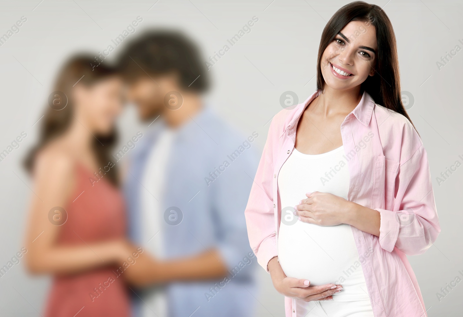 Image of Surrogate mother and intended parents against light grey background, selective focus
