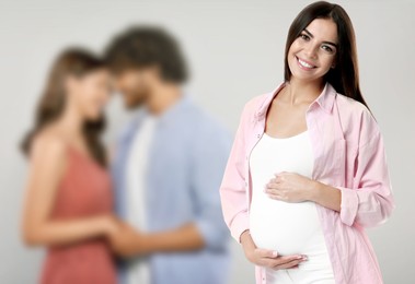 Image of Surrogate mother and intended parents against light grey background, selective focus