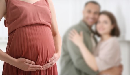Image of Surrogate mother and intended parents indoors, selective focus