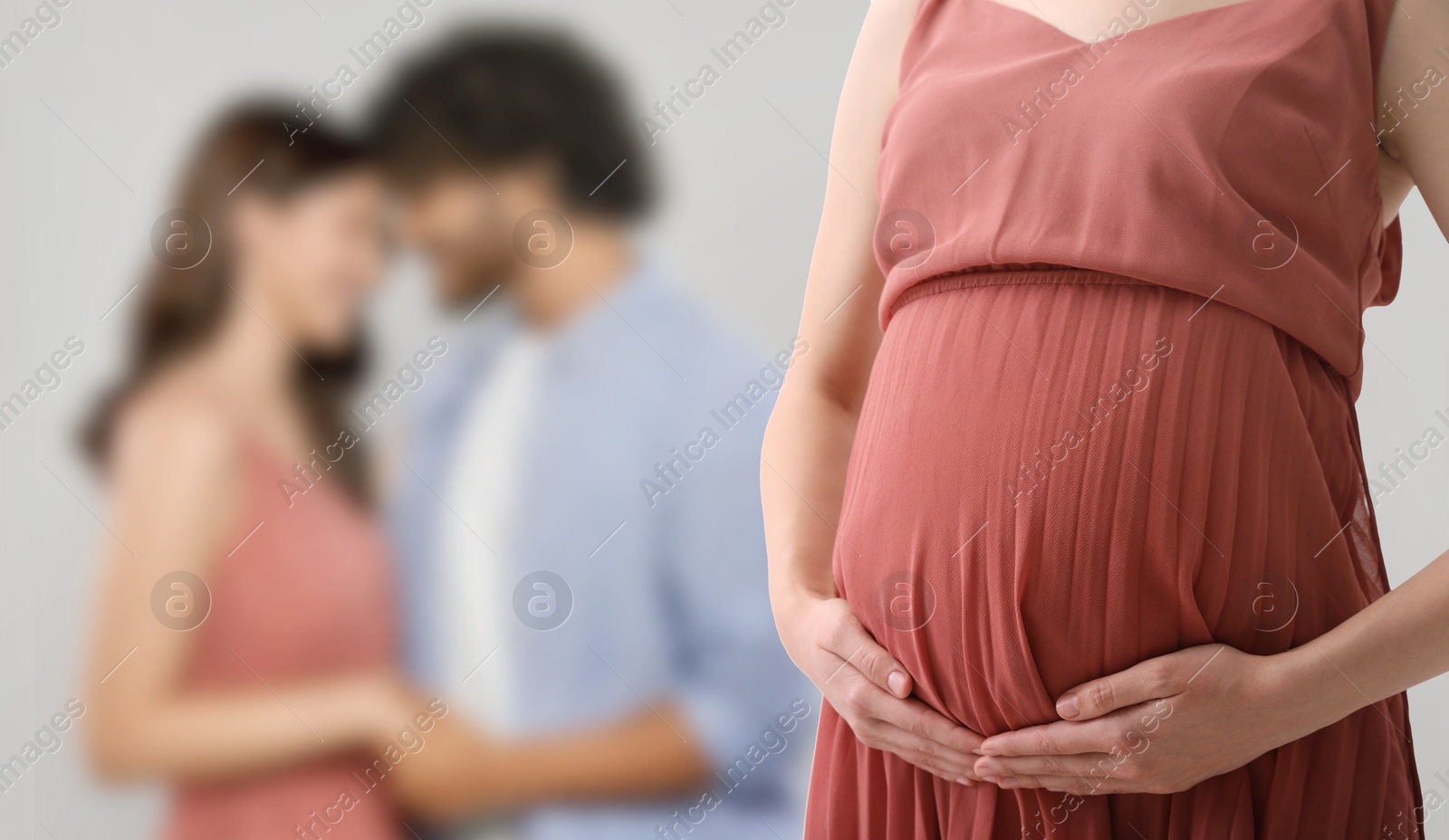 Image of Surrogate mother and intended parents against light grey background, selective focus