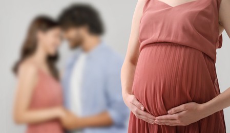 Image of Surrogate mother and intended parents against light grey background, selective focus