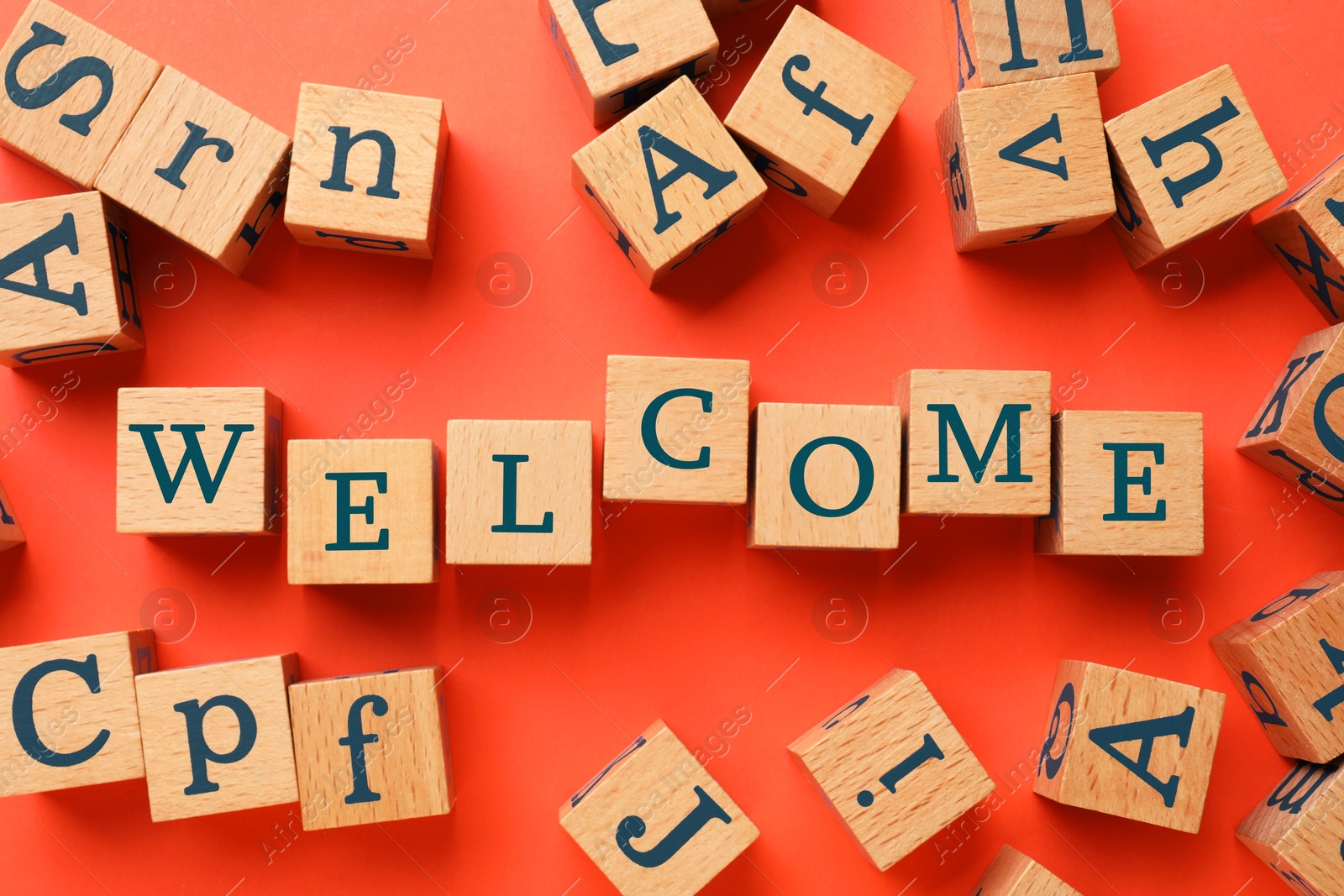 Word Welcome made of wooden cubes on red background, flat lay Image of Word Welcome made of wooden cubes on red background, flat lay