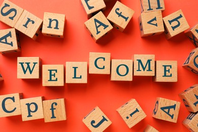 Image of Word Welcome made of wooden cubes on red background, flat lay