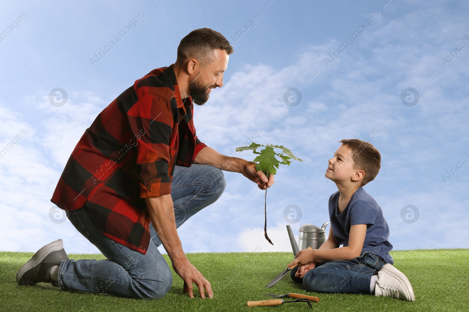 Image of Father and his son planting tree into ground outdoors