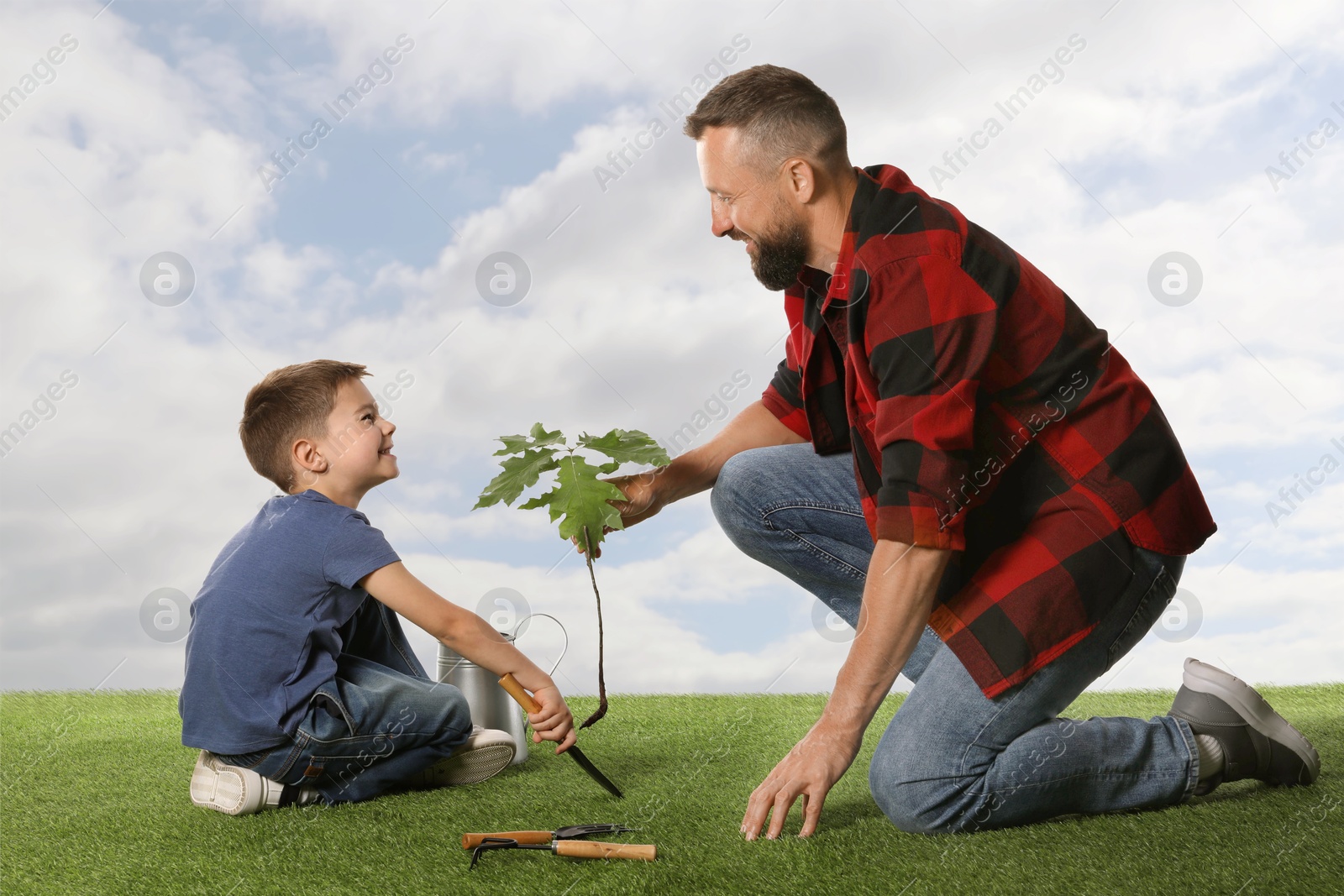 Image of Father and his son planting tree into ground outdoors