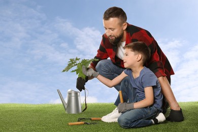 Image of Father and his son planting tree into ground outdoors