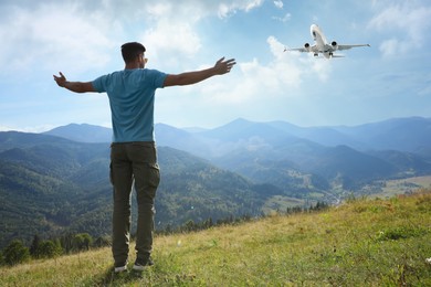 Image of Man in mountains looking at airplane flying in sky, back view