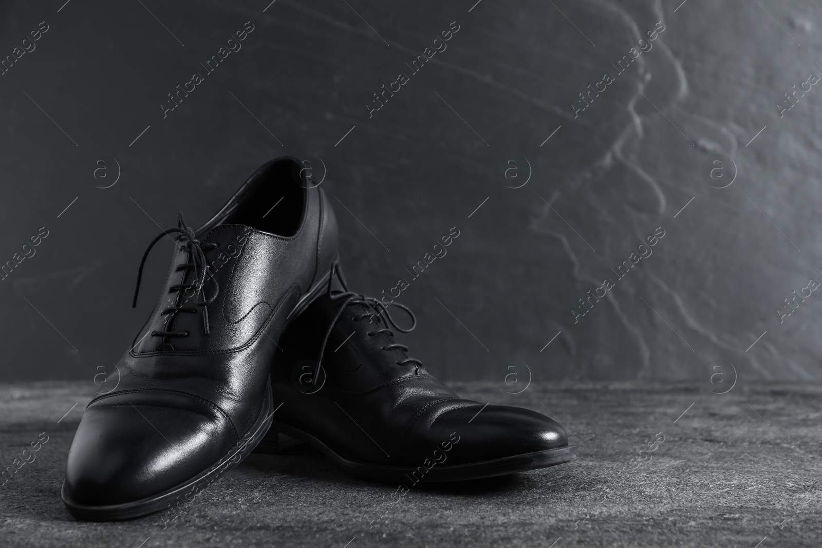 Photo of Pair of black leather shoes on grey surface, closeup. Space for text