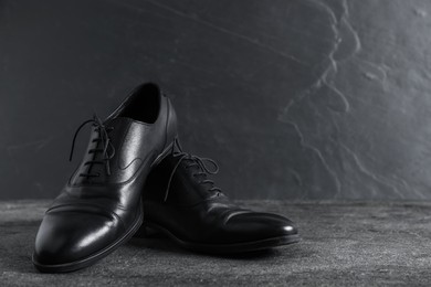 Photo of Pair of black leather shoes on grey surface, closeup. Space for text