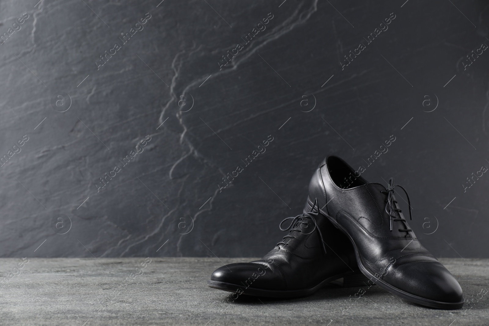 Pair of black leather shoes on grey surface, space for text Photo of Pair of black leather shoes on grey surface, space for text