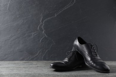 Photo of Pair of black leather shoes on grey surface, space for text