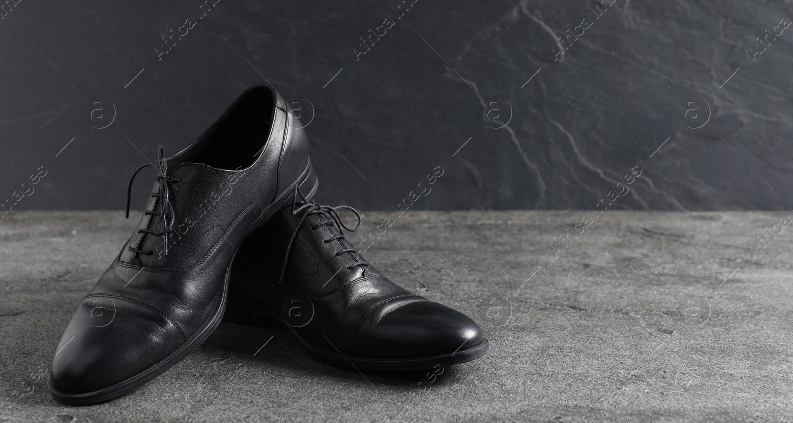 Photo of Pair of black leather shoes on grey surface, closeup. Space for text