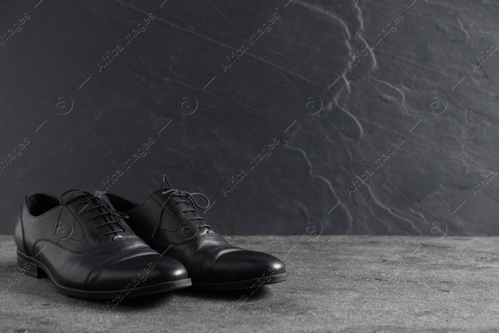 Pair of black leather shoes on grey surface, space for text Photo of Pair of black leather shoes on grey surface, space for text