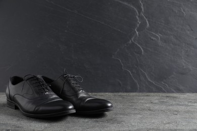 Photo of Pair of black leather shoes on grey surface, space for text