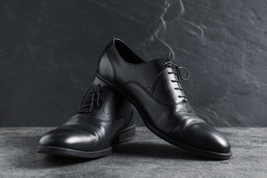 Photo of Pair of black leather shoes on grey surface