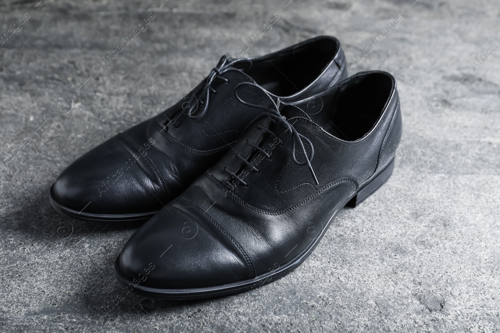 Photo of Pair of black leather shoes on grey surface, closeup